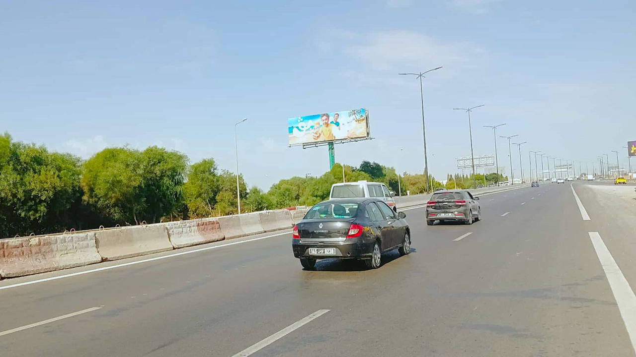 Panneau publicitaire UV26 – Niveau bretelle sortie Banlieue Sud, à 1km du centre commercial Azur City, niveau maisons Alfa Ford et Hyundai, direction Tunis